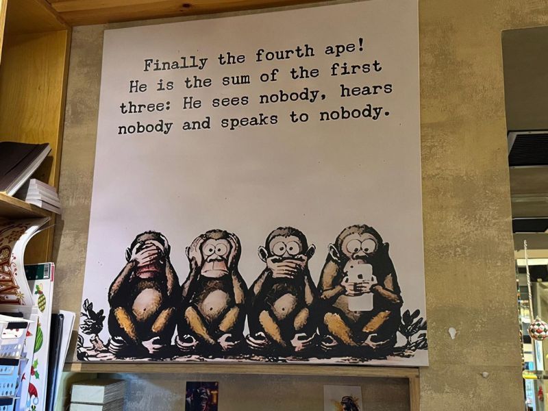 צילום של קיר עם פוסטר עם ארבעה קופים שהרביעי עם סמרטפון ביד